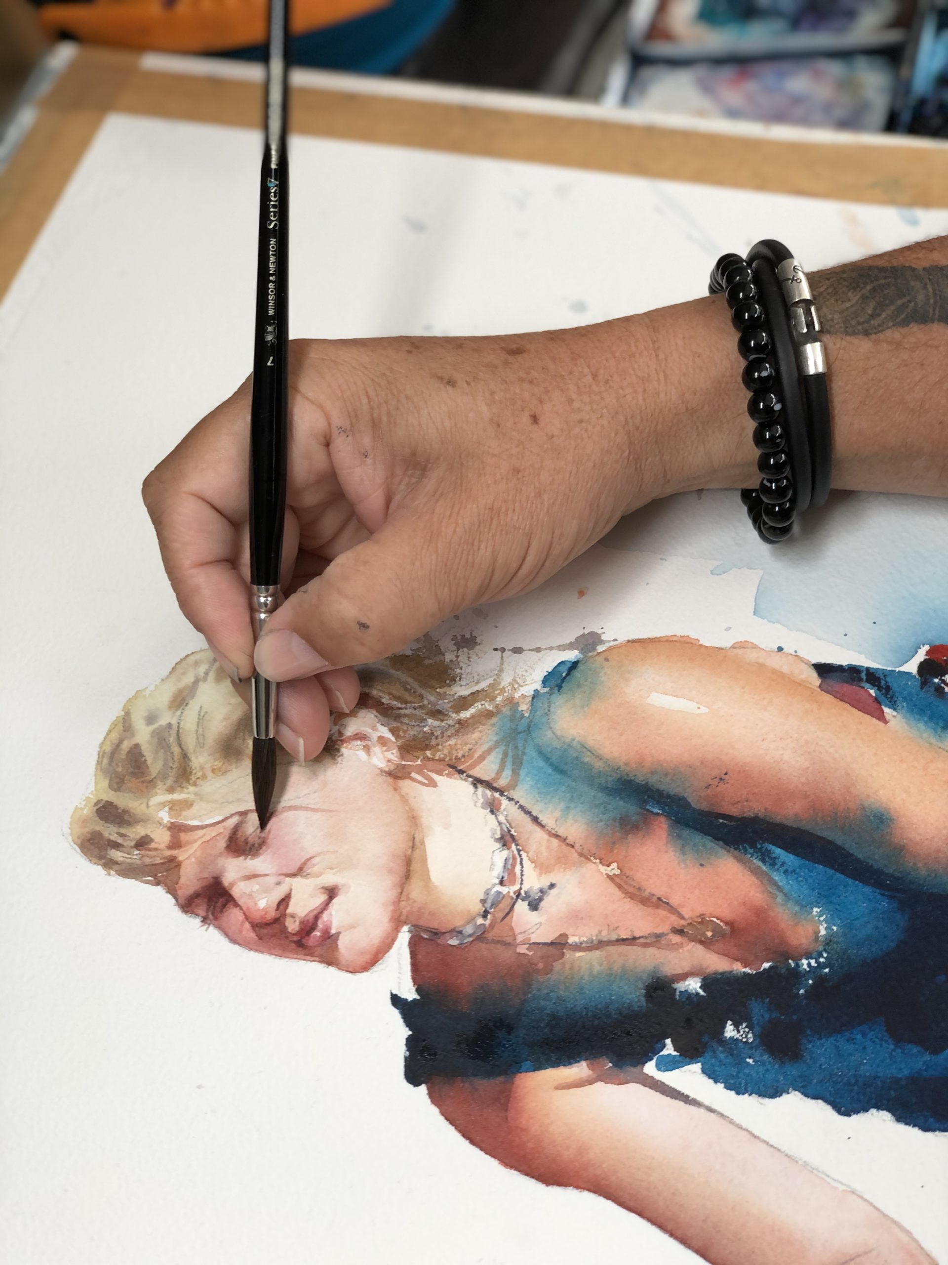 artist's hand with watercolor portrait