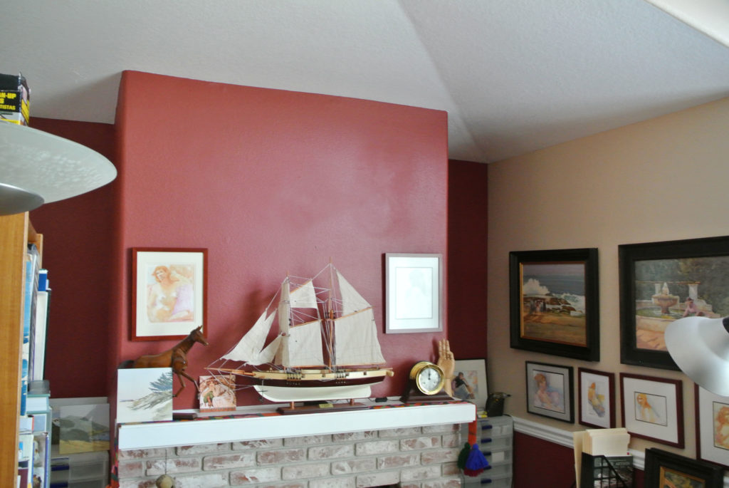 Artists' studio with paintings on the walls and model ship on fireplace mantle