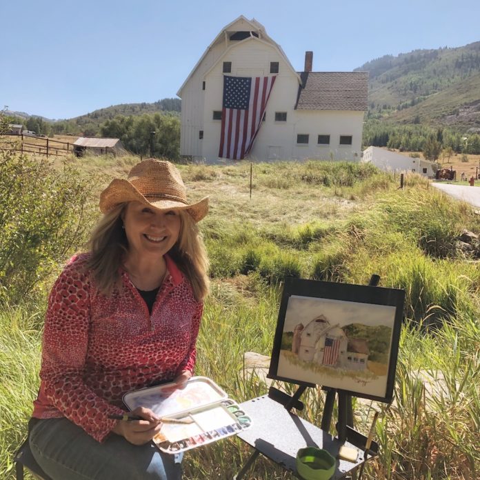 Watercolor artist working on a plein air painting of a barn