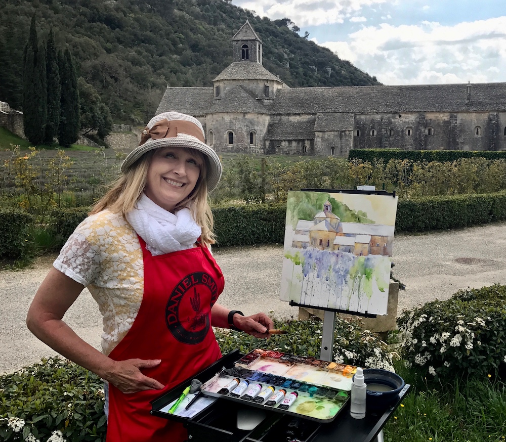 Watercolor artist plein air painting in France at an abbey