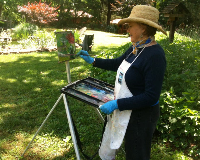 Female artist painting outdoors in a garden