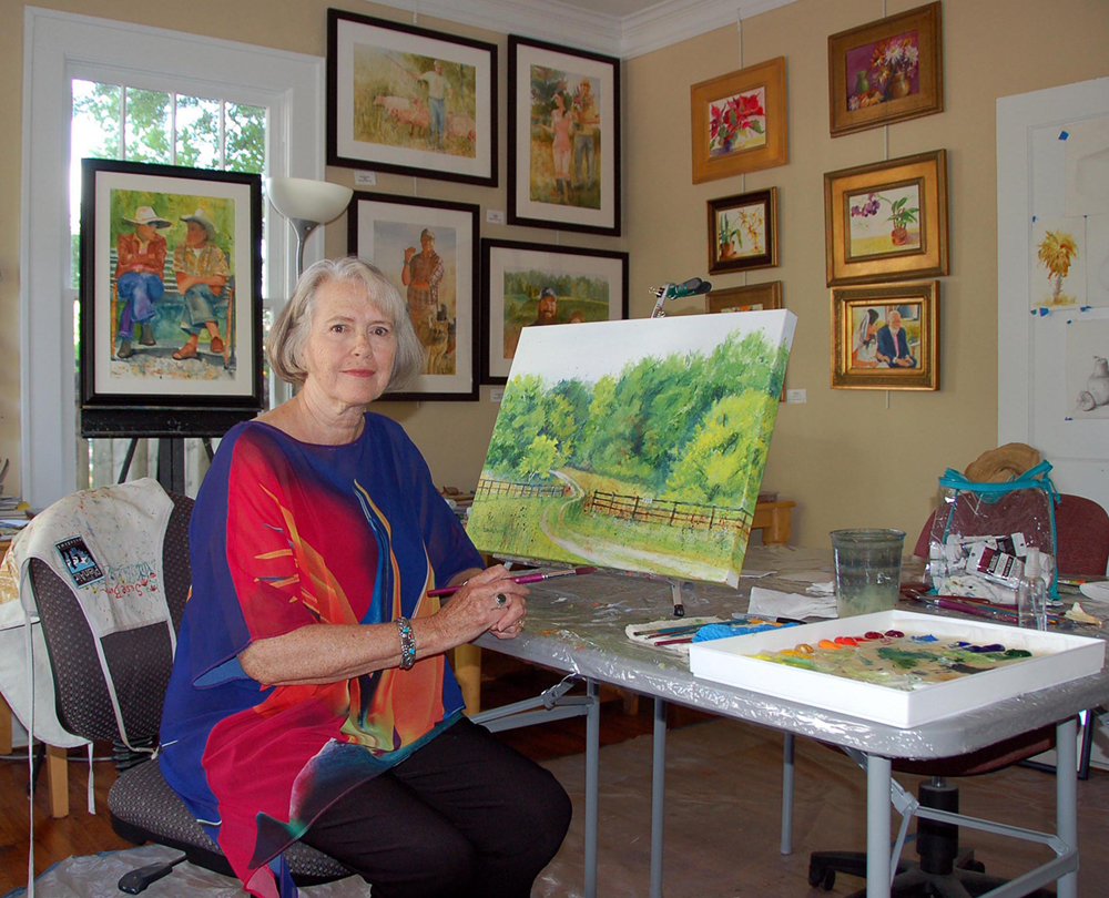 Artist painting in her studio with paintings hanging on the walls