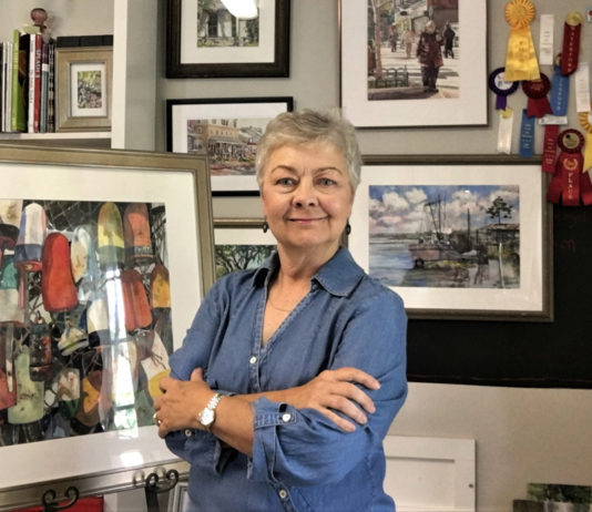 Female artist standing in front of her paintings
